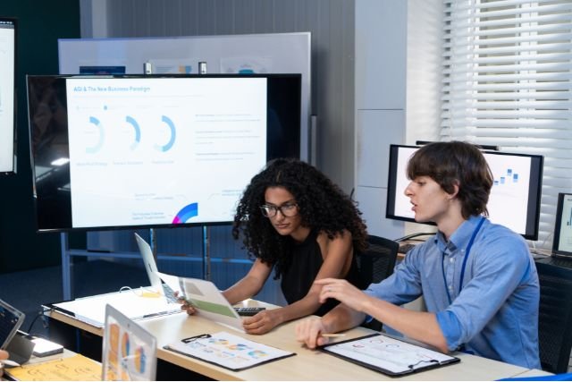 Two staff reviewing data on a computer screen